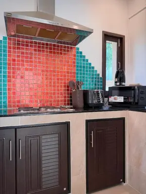a kitchen with orange and green tile on the wall at ozone pool villa phuket in Ban Pa Khlok