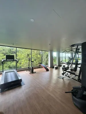 a gym with several exercise equipment in a room with windows at Hillside - Seashore Naiyang Beach in Phuket