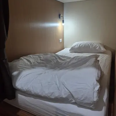 a bed with white sheets and pillows in a room at HOM's HOSTEL in Phuket Town