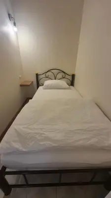 a bed in a small room with a white bedsheet at HOM's HOSTEL in Phuket Town