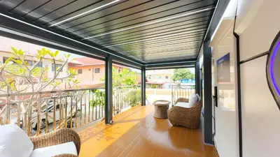a screened porch with wicker chairs on a balcony at Luxury Capsule Haus Phuket in Panwa Beach