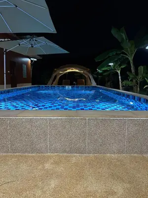 a swimming pool at night with an umbrella at Luxury Capsule Haus Phuket in Panwa Beach