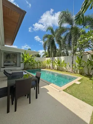 a patio with a table and chairs next to a swimming pool at Trichada Tropical Private Tropical 3BR Pool Villa in Laguna Phuket