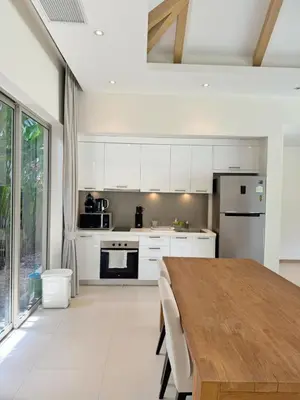 a kitchen with white cabinets and a wooden table at Trichada Tropical Private Tropical 3BR Pool Villa in Laguna Phuket