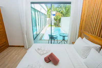 a bedroom with a bed and a view of a pool at White Villa Phuket in Ban Saiyuan (1)
