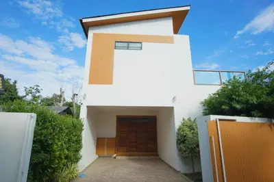 a white house with a brown door on it at White Villa Phuket in Ban Saiyuan (1)