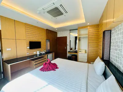a bedroom with a large white bed and a television at Anda Beachside Hotel in Karon Beach