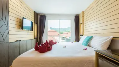 a bedroom with a large bed with a large window at Anda Beachside Hotel in Karon Beach