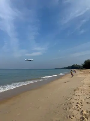 an airplane is flying over a beach with people walking at VIP Great Hill Airport in Phuket