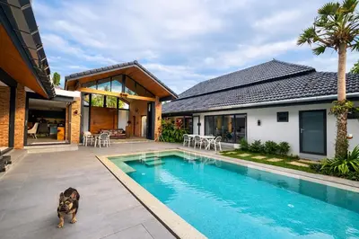 a dog sitting next to a swimming pool in a house at Golf Paradise 4 BR Smart Home Pool Villa at Loch Palm Golf Course Kathu in Ban Kathu