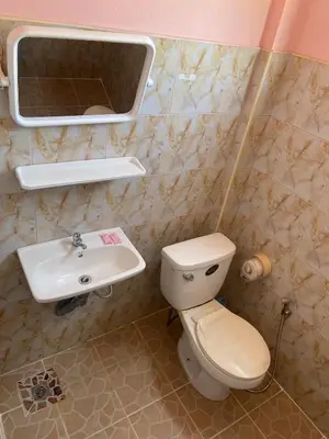 a bathroom with a toilet and a sink at Kittiya Mansion in Ban Phlu Nai
