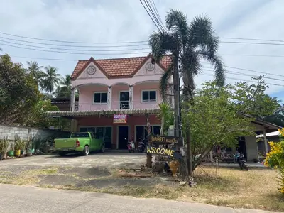 a pink house with a welcome sign in front of it at Kittiya Mansion in Ban Phlu Nai