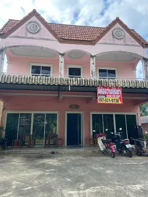 a pink building with motorcycles parked in front of it at Kittiya Mansion in Ban Phlu Nai