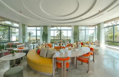 a large room with a yellow couch and tables and chairs at Casa tua, luxury 2bed - Canvas by Sansiri in Laguna Phuket