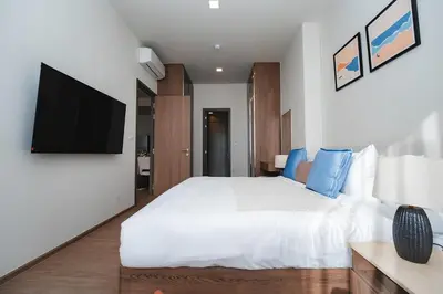 a bedroom with a white bed and a flat screen tv at Casa tua, luxury 2bed - Canvas by Sansiri in Laguna Phuket