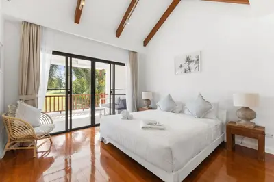 a white bedroom with a bed and a chair at Coastal Villa on Fairway 3 Bedroom in Laguna Phuket