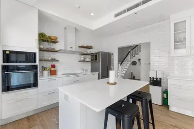 a white kitchen with a white counter and stools at Coastal Villa on Fairway 3 Bedroom in Laguna Phuket