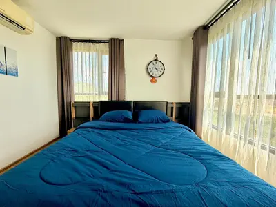 a bedroom with a blue bed with a clock on the wall at MiCasa - 2BR Centrio 7th Floor in Ban Rangeng