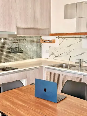a laptop computer sitting on a wooden table in a kitchen at MiCasa - 2BR Centrio 7th Floor in Ban Rangeng