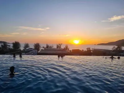 a group of people in a swimming pool at sunset at Beachfront 1 Deluxe BR Luxury Pool Patong Phuket in Patong Beach