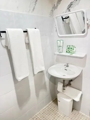 a white bathroom with a sink and a mirror at Top hotel in Patong Beach