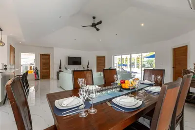 a dining room and living room with a table and chairs at Elegant 2BR Pool Villa Overlooking Loch Palm Golf - Baan Sawan Garden Villa in Kathu
