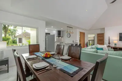 a dining room and living room with a wooden table at Elegant 2BR Pool Villa Overlooking Loch Palm Golf - Baan Sawan Garden Villa in Kathu