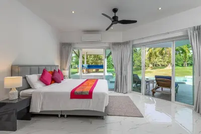 a bedroom with a king sized bed and a patio at Elegant 2BR Pool Villa Overlooking Loch Palm Golf - Baan Sawan Garden Villa in Kathu
