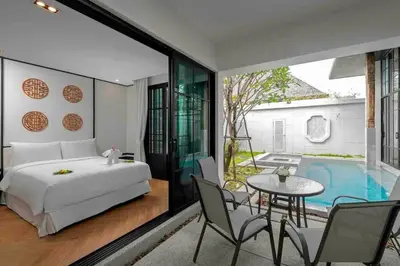 a bedroom with a bed and a table and a pool at Mono Villas Pasak - Three Bedroom Pool Villa in Bangtao in Ban Pak Lak
