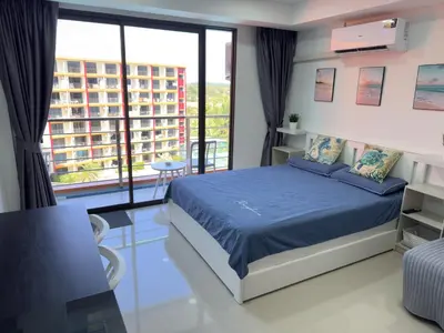 a bedroom with a bed and a large window at 777 Beach Condo in Ban Mai Salae