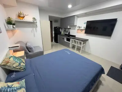 a living room with a blue bed and a kitchen at 777 Beach Condo in Ban Mai Salae