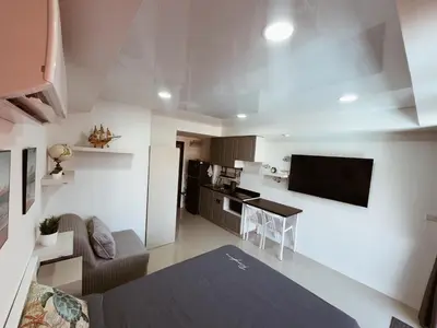 a small kitchen and living room with a couch and a television at 777 Beach Condo in Ban Mai Salae