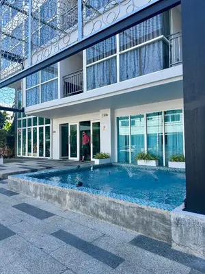 a person standing in front of a building with a swimming pool at Phuket Kata Studio Apartment in Kata Beach