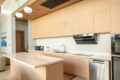 a kitchen with white countertops and wooden cabinets at Holiday pool villa in Ban Na Nai