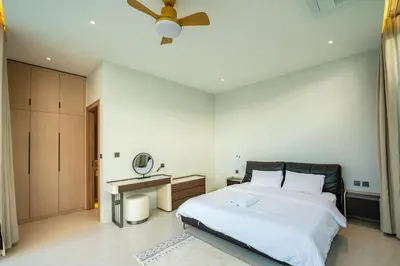 a bedroom with a large bed and a table at Holiday pool villa in Ban Na Nai