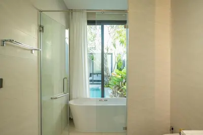 a bathroom with a tub and a shower with a window at Holiday pool villa in Ban Na Nai
