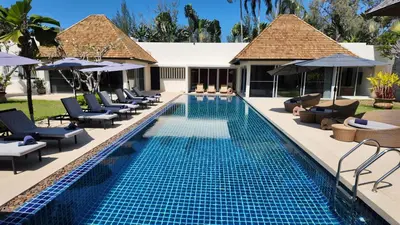 a swimming pool with chairs and umbrellas in a resort at Villa Samakee Luxury 5 Bedroom Villa in Ban Thalat Choeng Thale