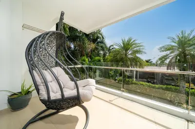 a swing chair sitting on a balcony with a window at 1 BR Balcony Pool and Garden View - Babylon Sky M206 in Rawai Beach