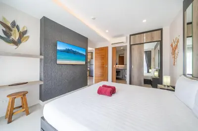 a bedroom with a large white bed with a red object on it at 1 BR Balcony Pool and Garden View - Babylon Sky M206 in Rawai Beach