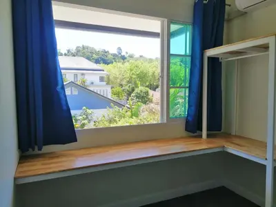 a window with blue curtains and a view of a house at TwinVillaSky in Ban Muang Mai