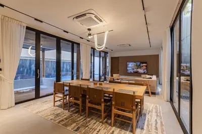 a dining room with a table and chairs and large windows at PRAIA Residence 4BR - Bangtao in Ban Pak Lak