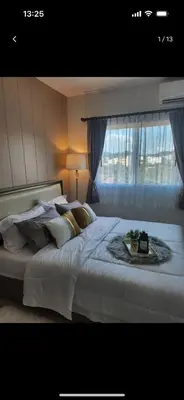 a bedroom with a large white bed with a window at Charming Condo in Wichit Comfort Meets Convenience in Ban Rangeng