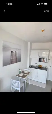 a kitchen with white cabinets and a table and chairs at Charming Condo in Wichit Comfort Meets Convenience in Ban Rangeng
