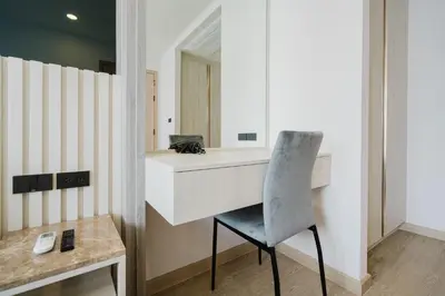 a bathroom with a vanity and a chair in front of a mirror at 1BR Ozon BangTao apartment in Laguna Phuket