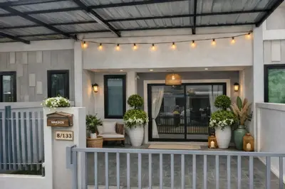 a house with plants in white vases on a porch at Bimi warm house in Ban Na Sat