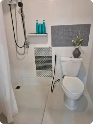 a white bathroom with a toilet and a shower at Bimi warm house in Ban Na Sat
