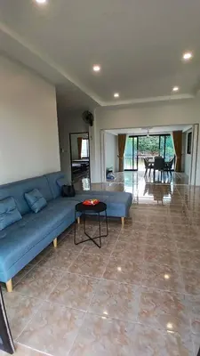 a living room with a blue couch and a table at Janjira sea view pool villa in Ban Ko Kwang