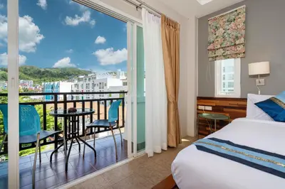 a bedroom with a bed and a balcony with a view at SawasdeeCiao Patong Guesthouse in Patong Beach