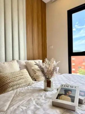 a picture and a vase of flowers on a bed at The Cust Phuket in Ban Khok Chang