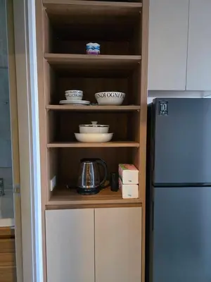 a kitchen with a cupboard with dishes and a refrigerator at The Cust Phuket in Ban Khok Chang